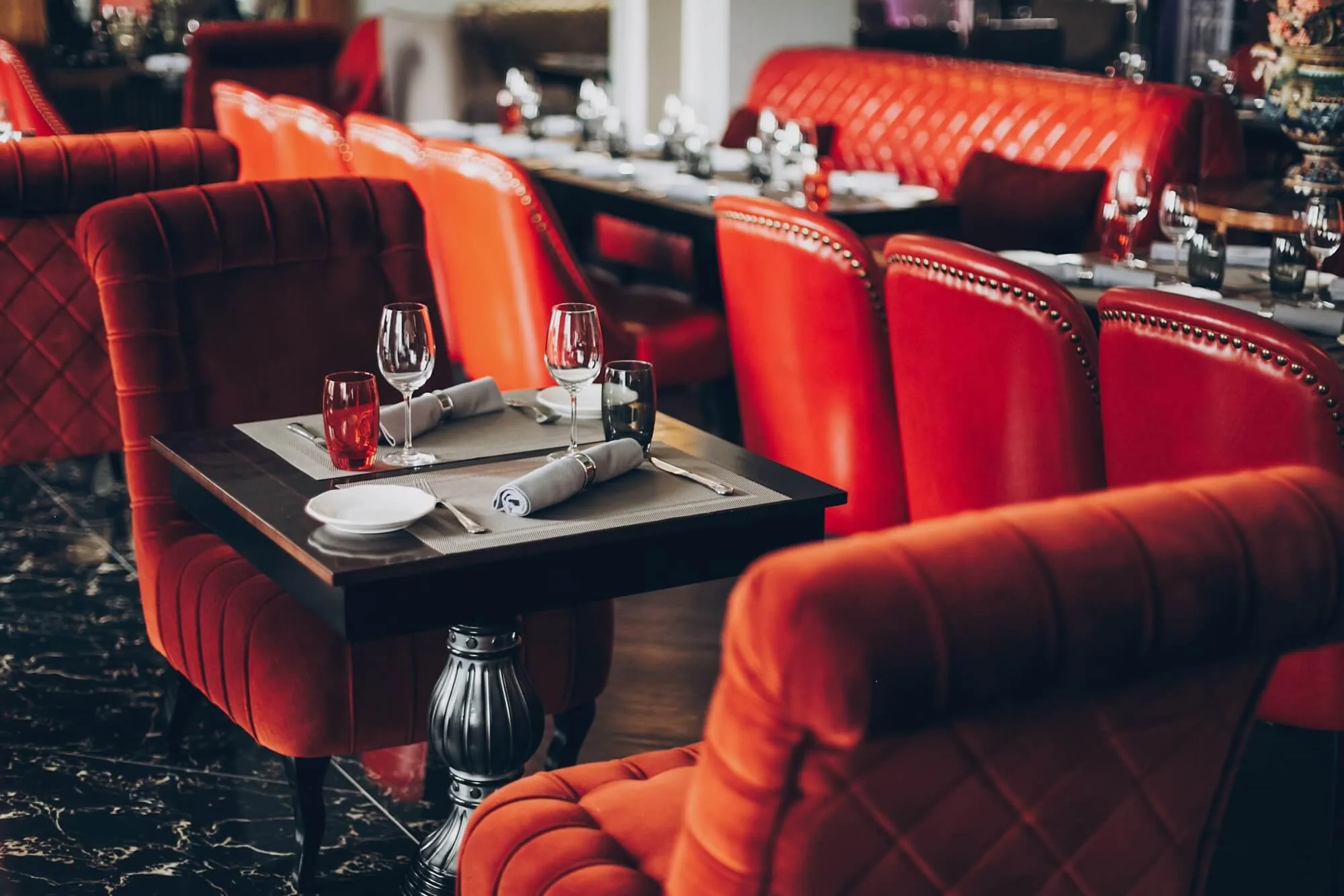 A restaurant table set beside red upholstered seating
